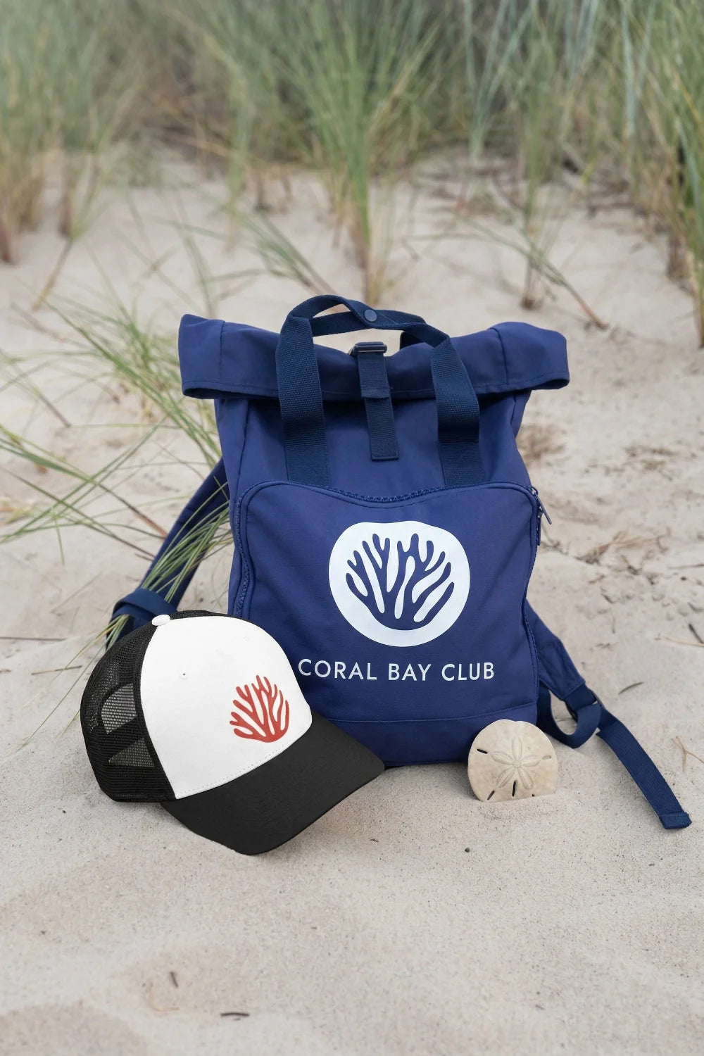 Rucksack und Trucker Cap der Marke "Coral Bay Club" liegt am Strand 